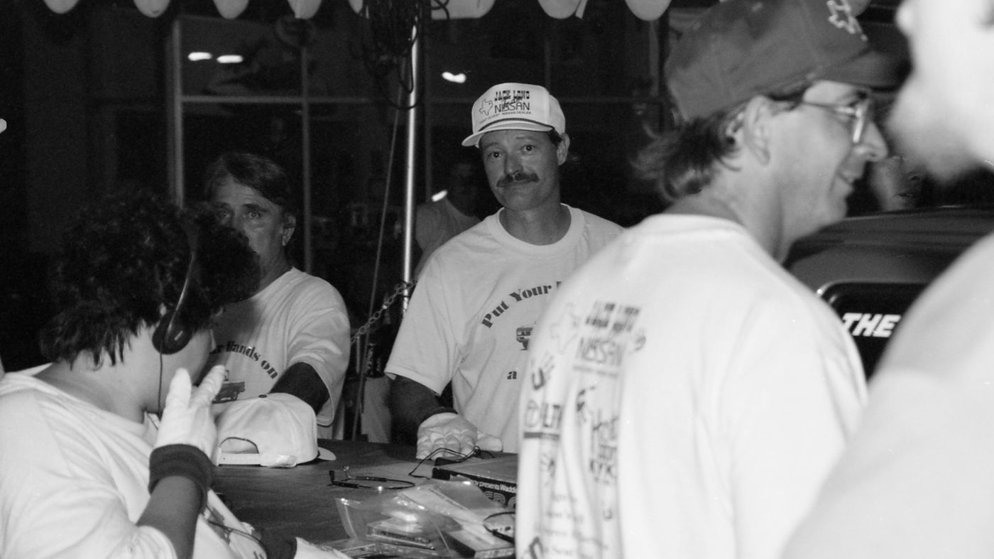 A contestant in a Jack Long Nissan cap looks toward the camera at night
